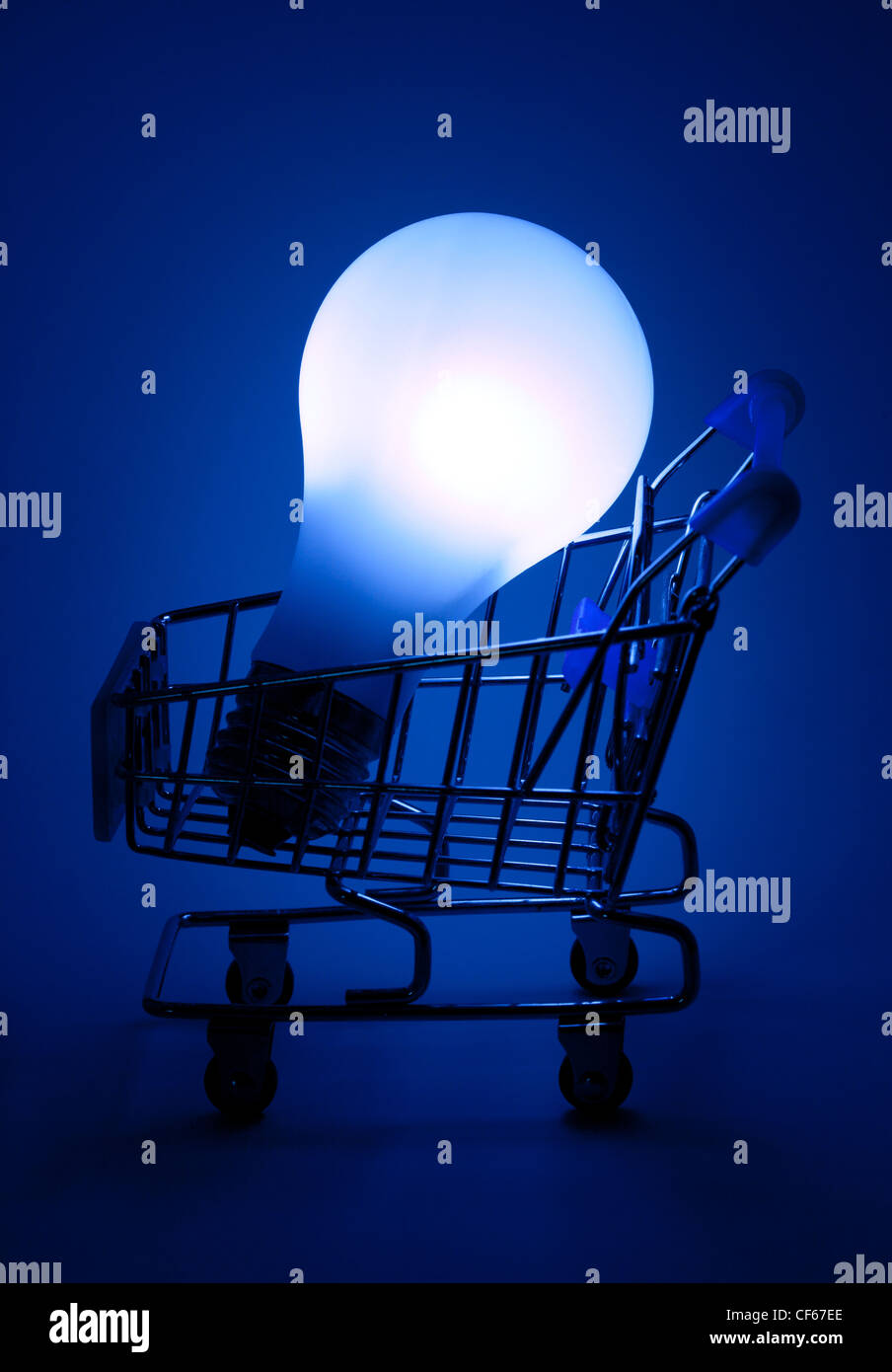 Shopping cart with light bulb in dark blue light. Stock Photo