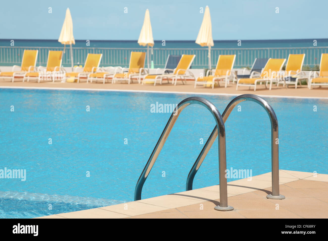 hotel swimming pool with stair, yellow longes and umbrellas Stock Photo