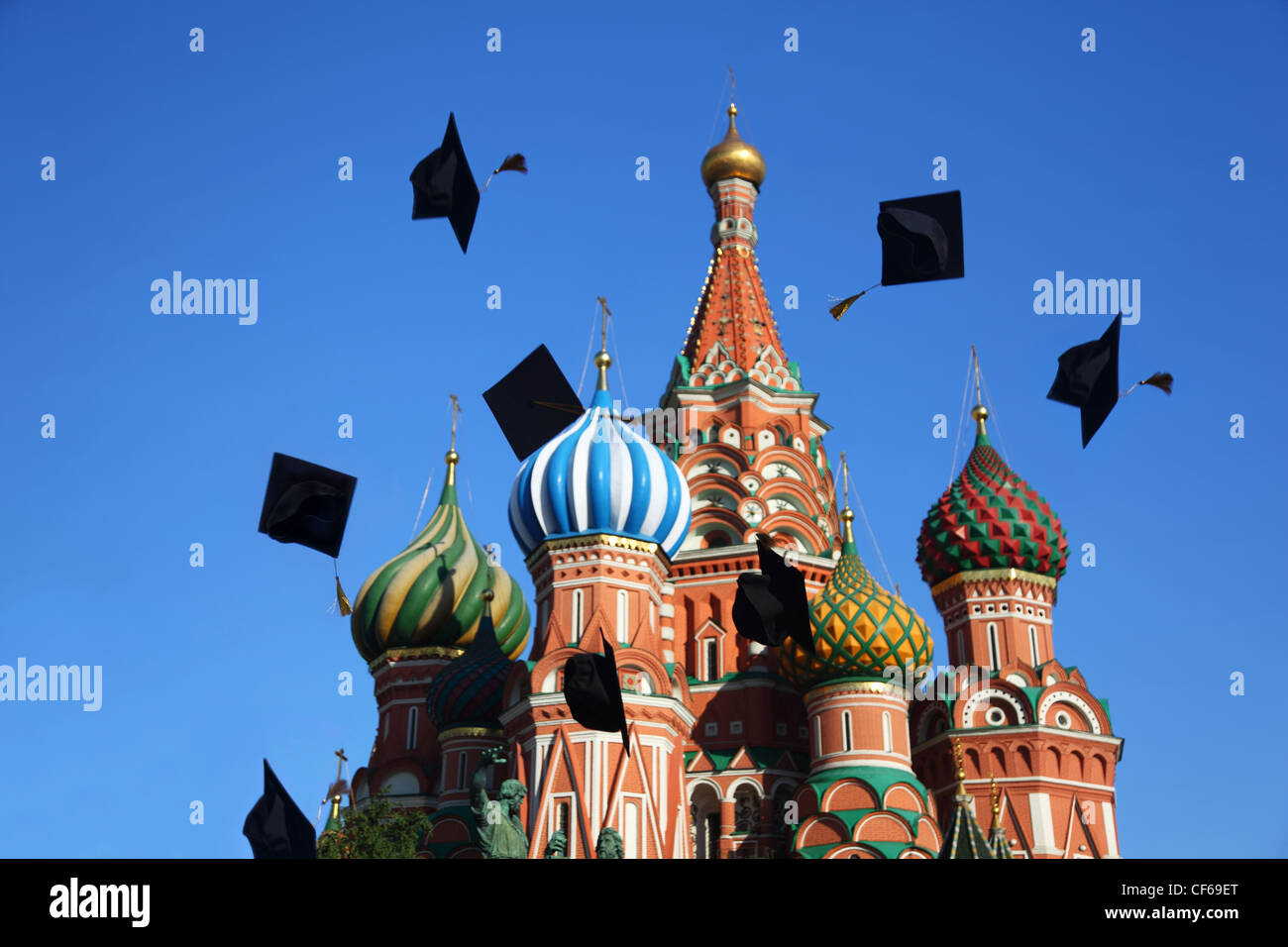 Black hats of graduation throw  in sky near St. Basil Cathedral. Moscow. Stock Photo