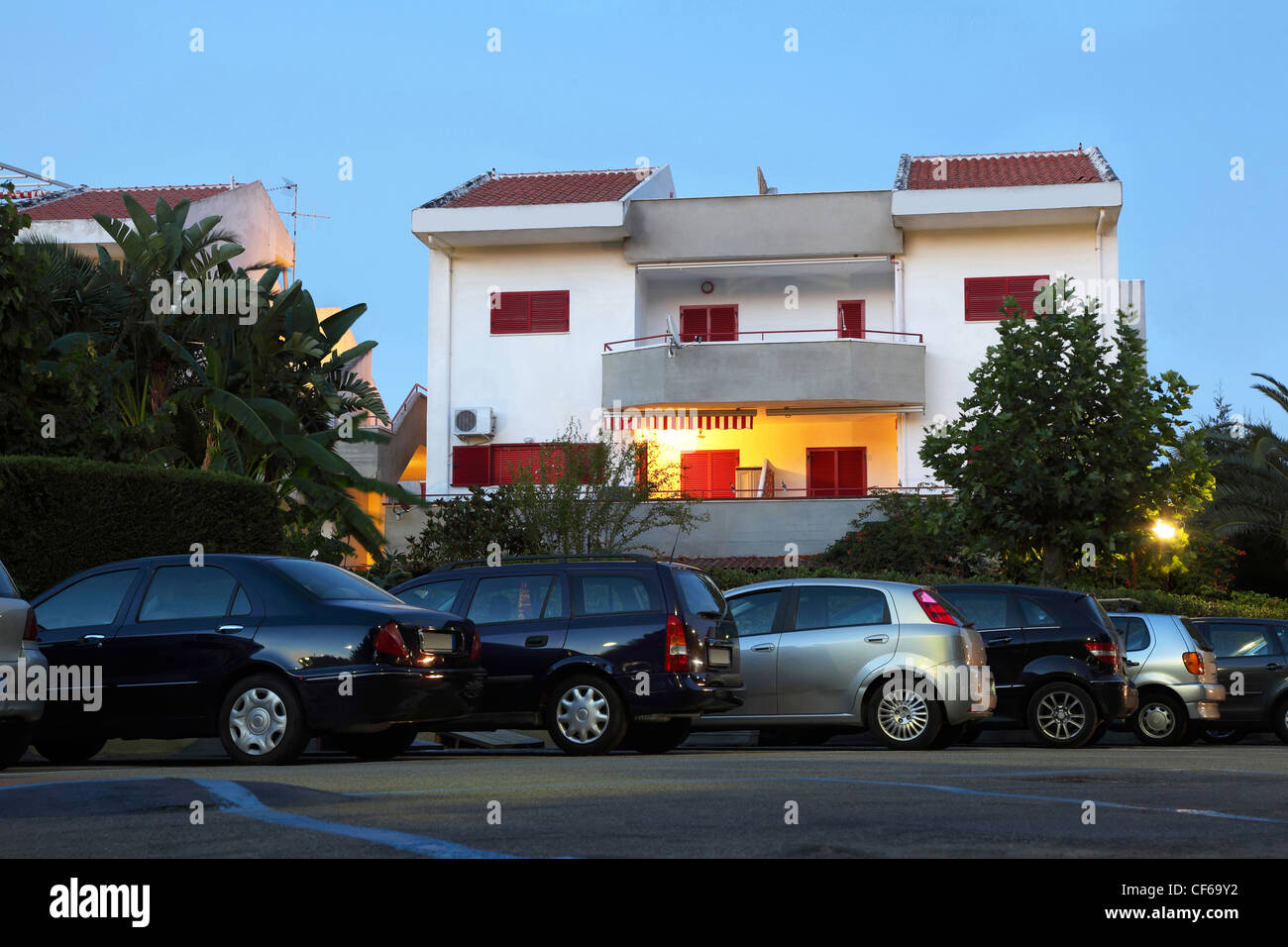 White two-storeyed cottage at front and parking place before neem Stock Photo