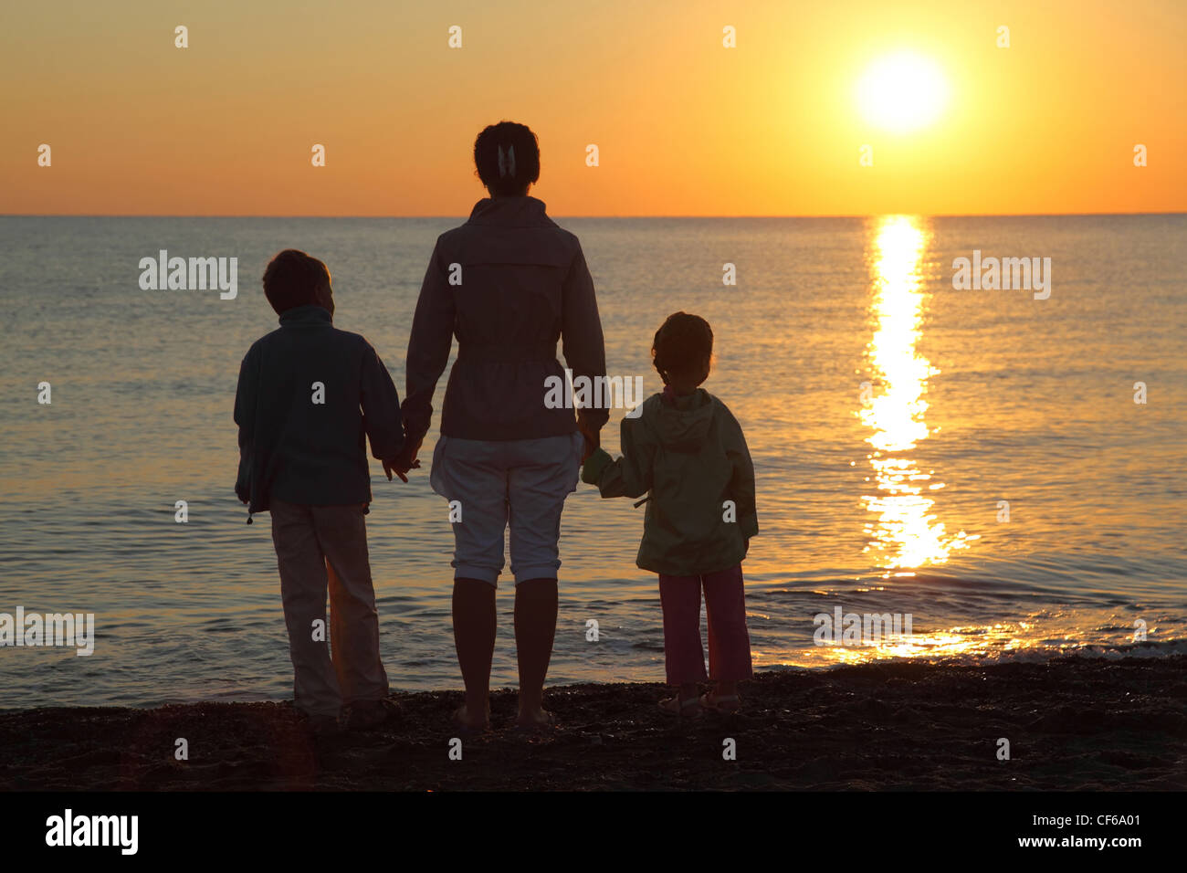 Mother with two children, embarking on hands stand on  beach  person to sea and look at sunset Stock Photo