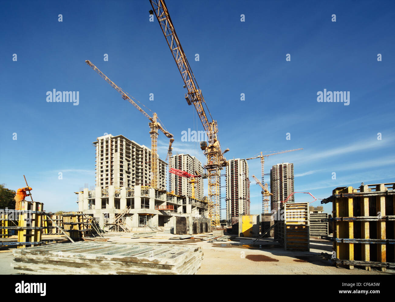 Working tall cranes inside place for with tall buildings under construction under a blue sky Stock Photo