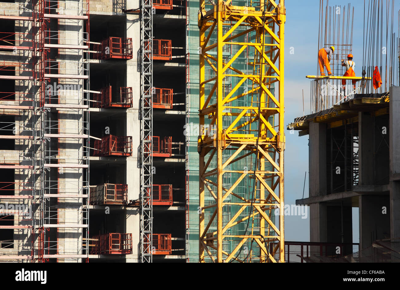 Two working people build high-rise building at high altitude Stock Photo