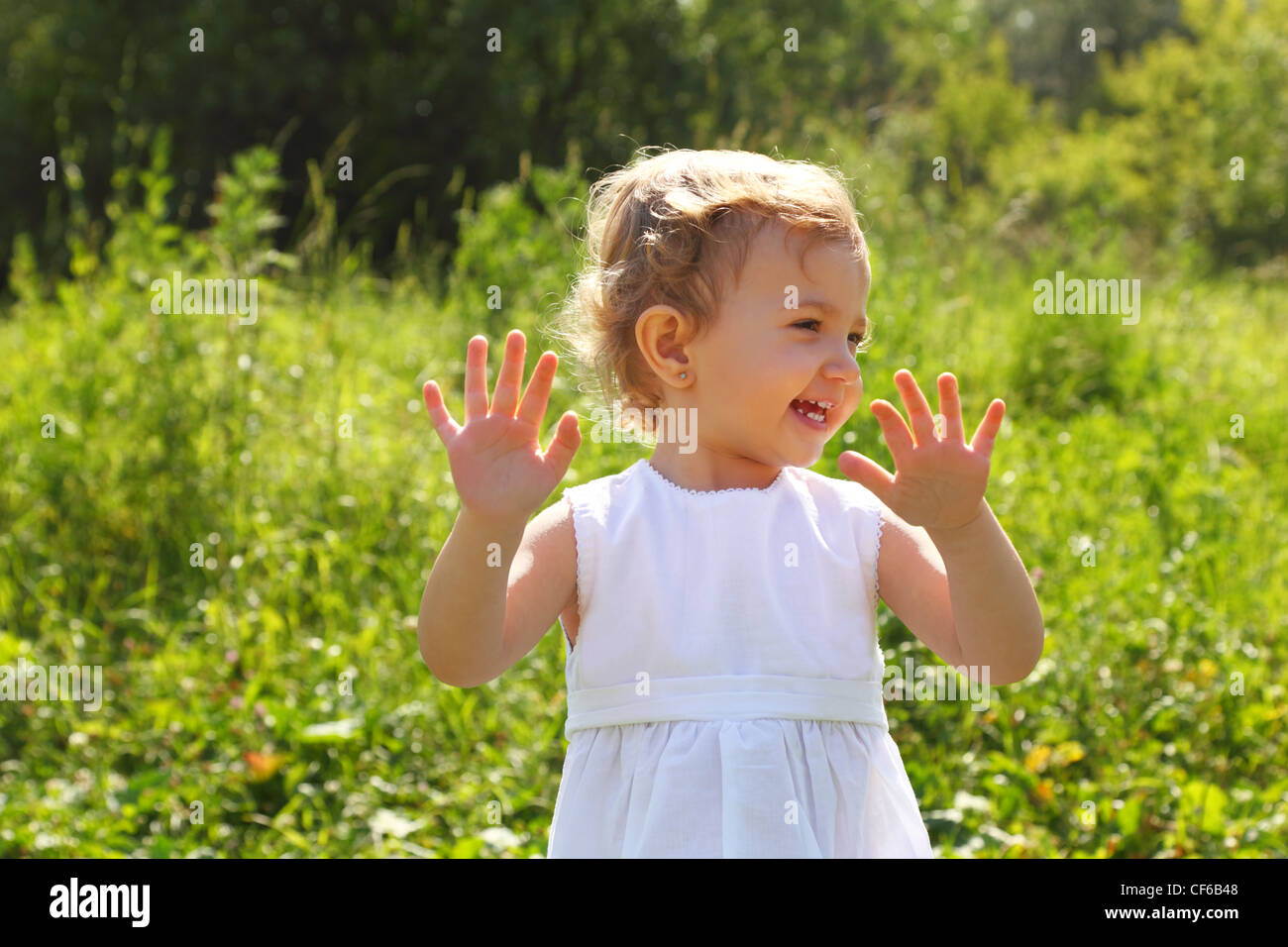 Laughing little girl standing in the grass Stock Photo