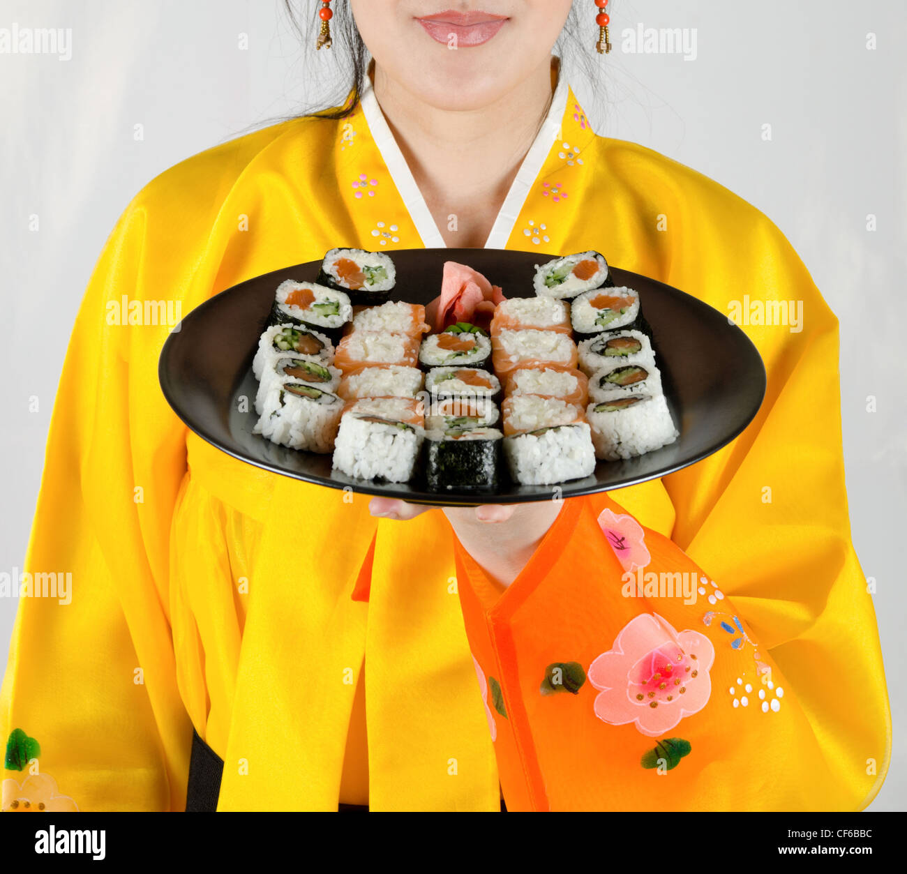 woman at bright cloth holding plate with fresh sushi set on it Stock Photo