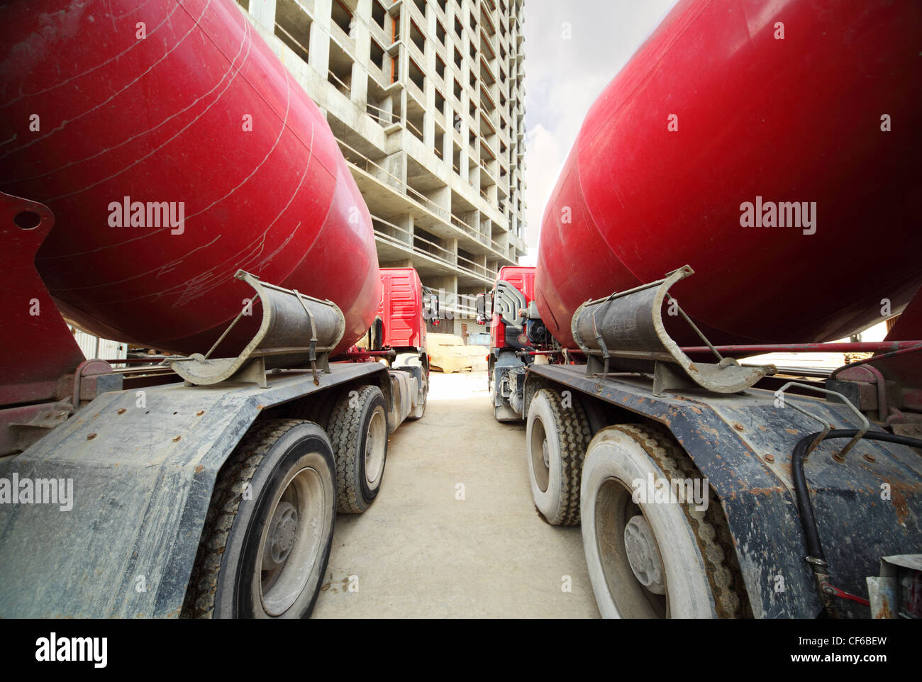 Between two concrete mixer standing near unfinished tall high-rise buildings Stock Photo
