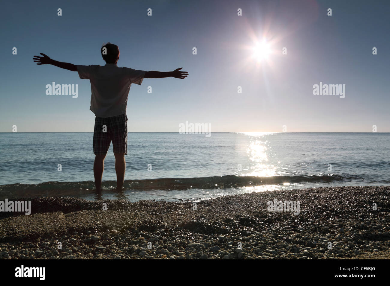 Man stands ashore in water and conducts hands in sides Stock Photo