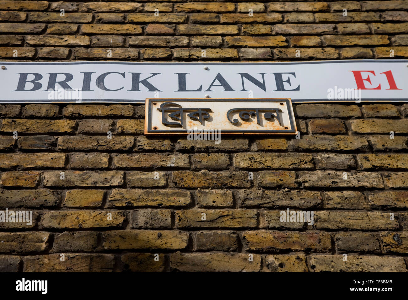 Looking up to the Brick Lane street sign on a brick wall in East London ...