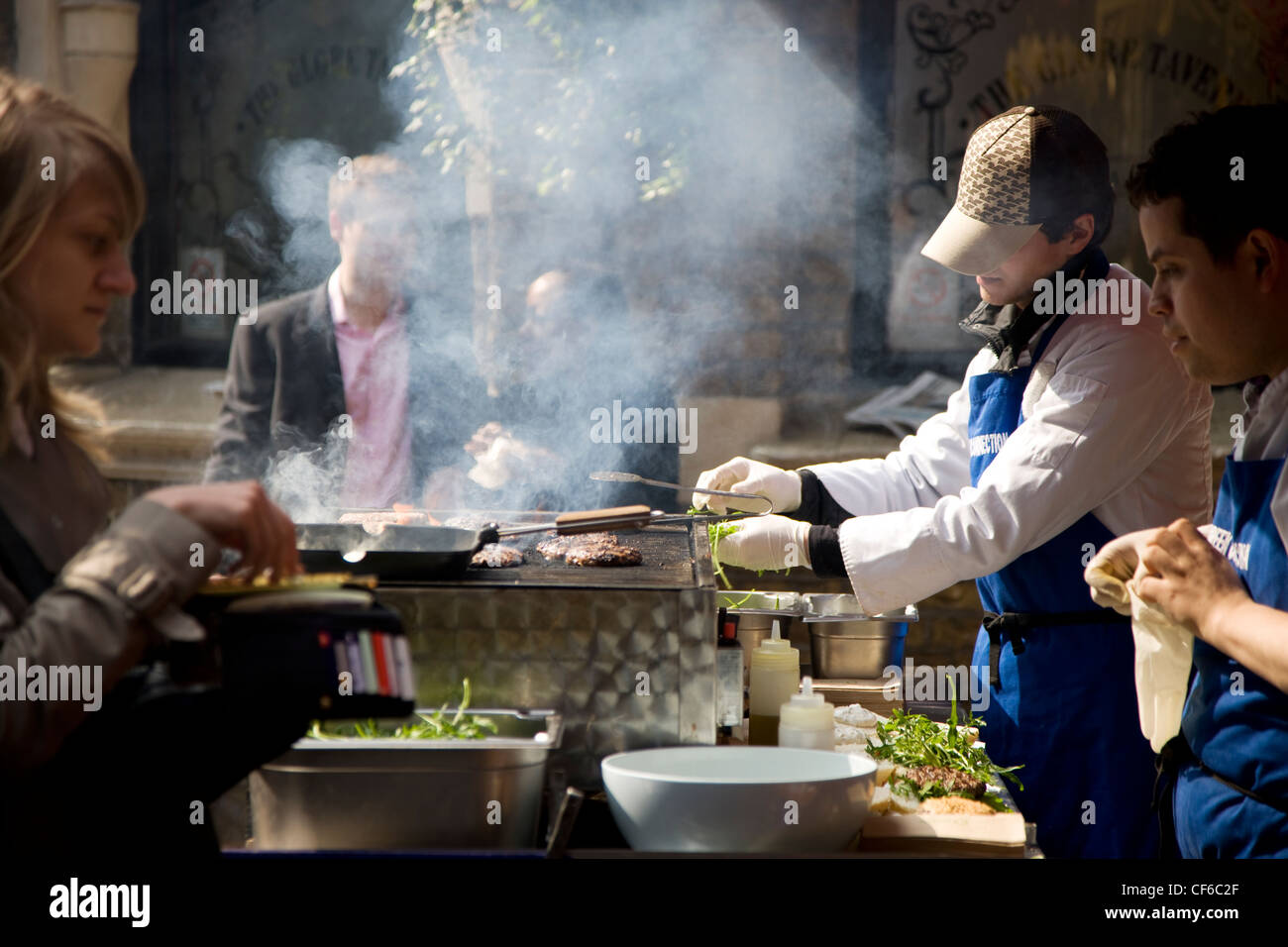 Customers watch as burgers are put onto a griddle in Borough Market. Stock Photo