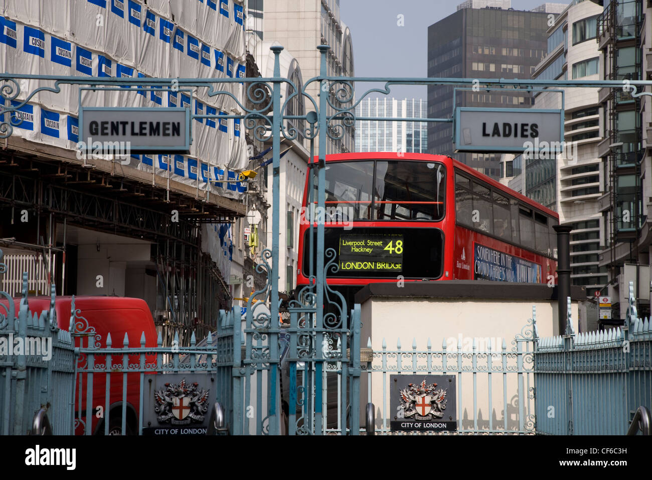 A double decker bus passes behind public conveniences in the City of London. Stock Photo