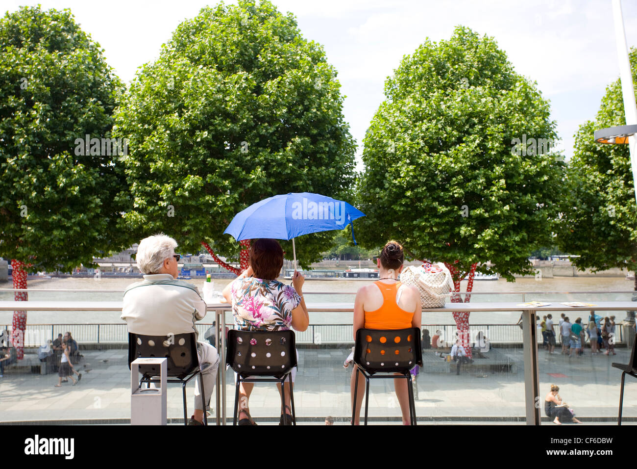 People seated on a balcony at the Royal Festival Hall looking out over the River Thames. Stock Photo