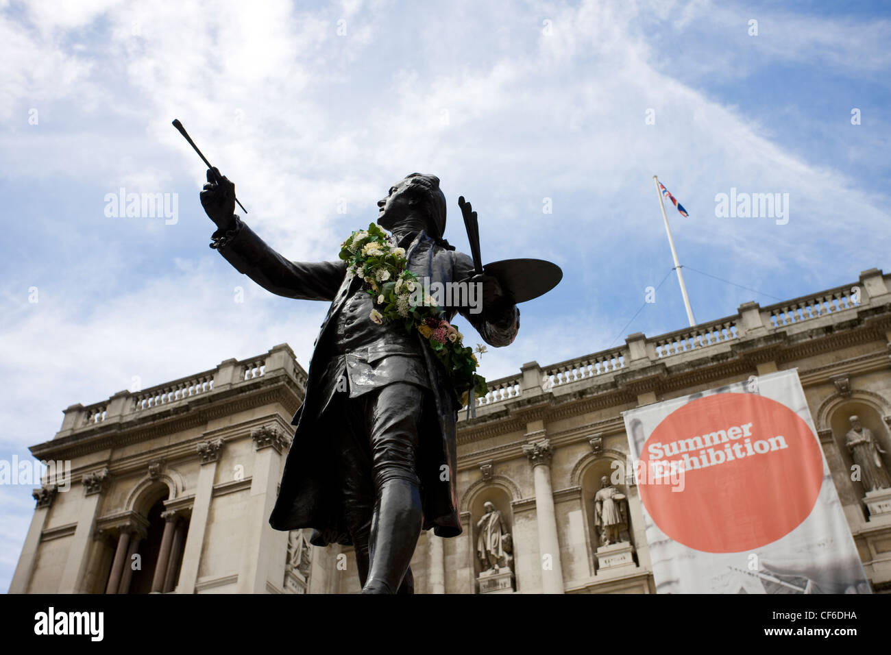 A sculpture of Sir Joshua Reynolds outside the Royal Academy of Arts in front of a large banner advertising the annual summer ex Stock Photo