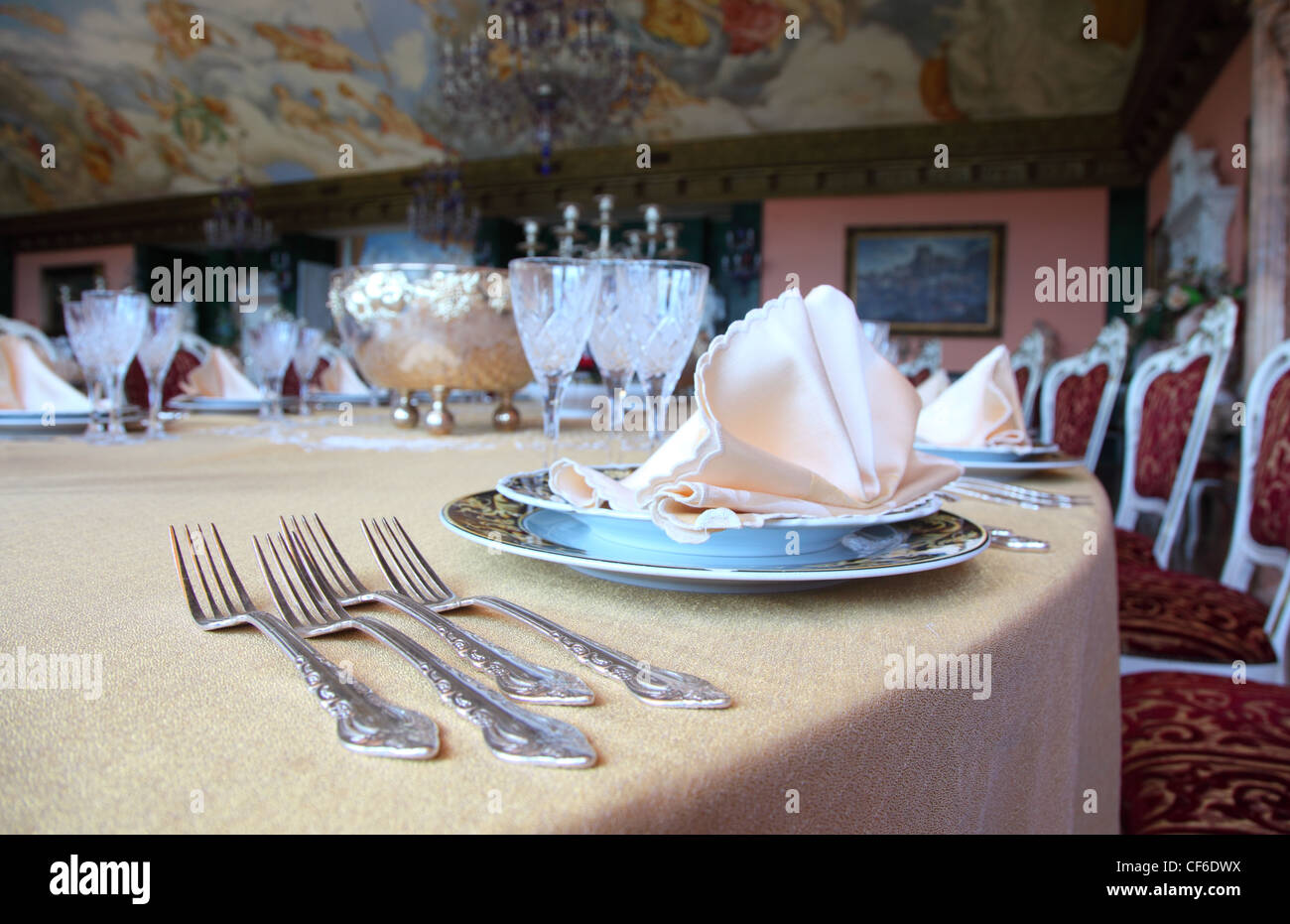 Four forks and two plates with placemat at the brink of dinner table in restaurant Stock Photo