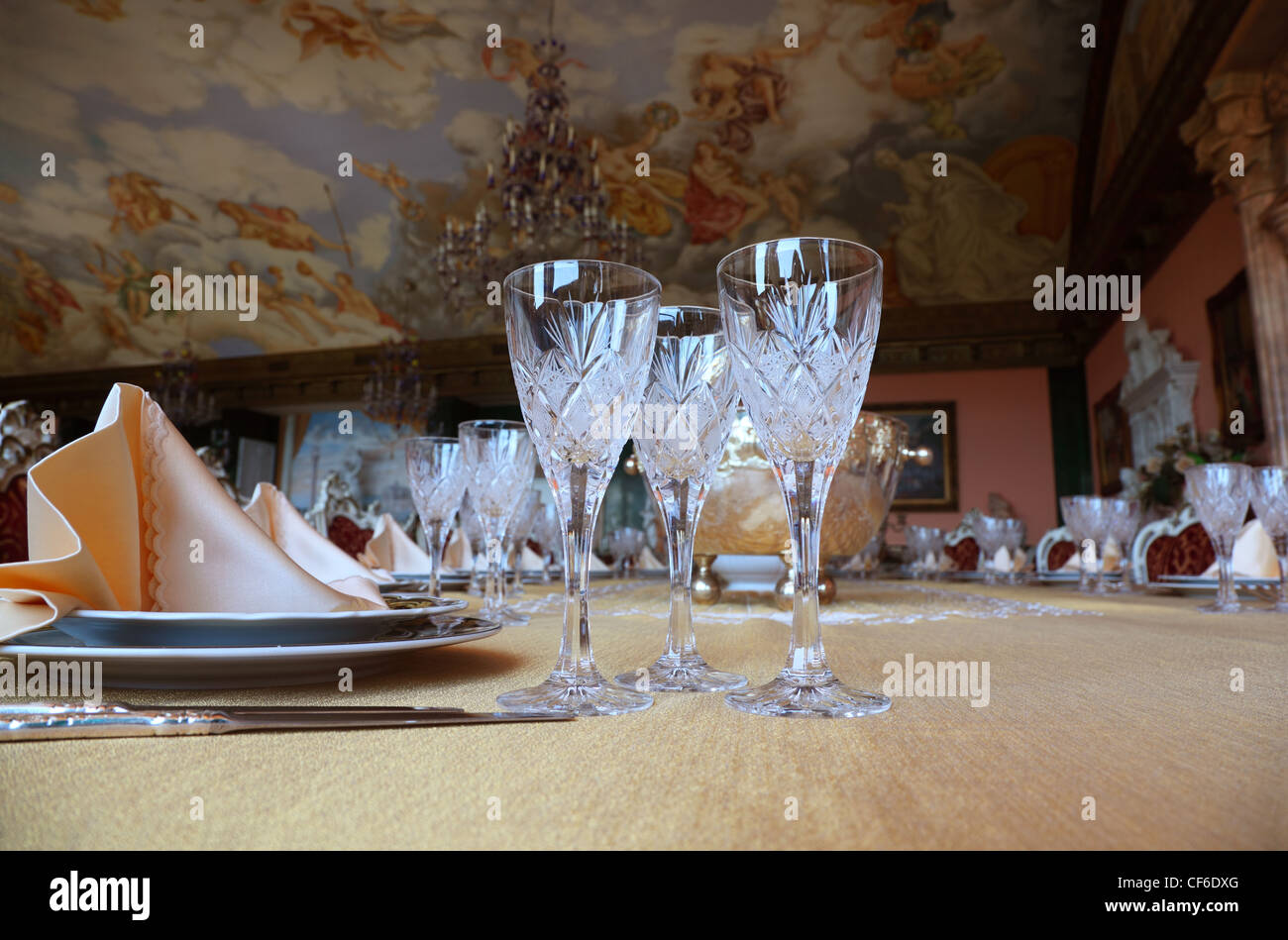 Three cut-glass gobles stand on big dinner table near knives and plates with placemats Stock Photo