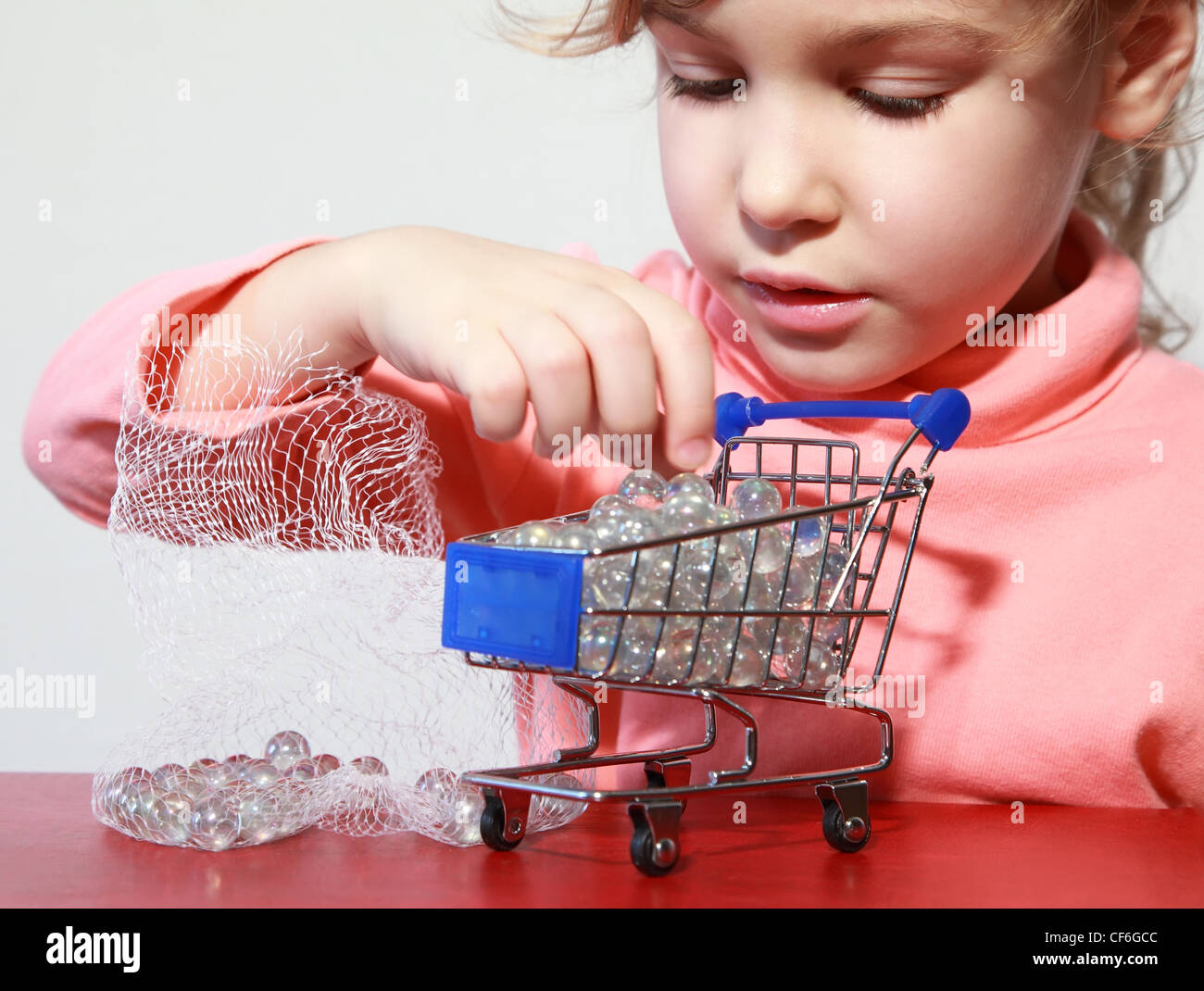 Cute little girl care play with toy shopping trolley filled by small