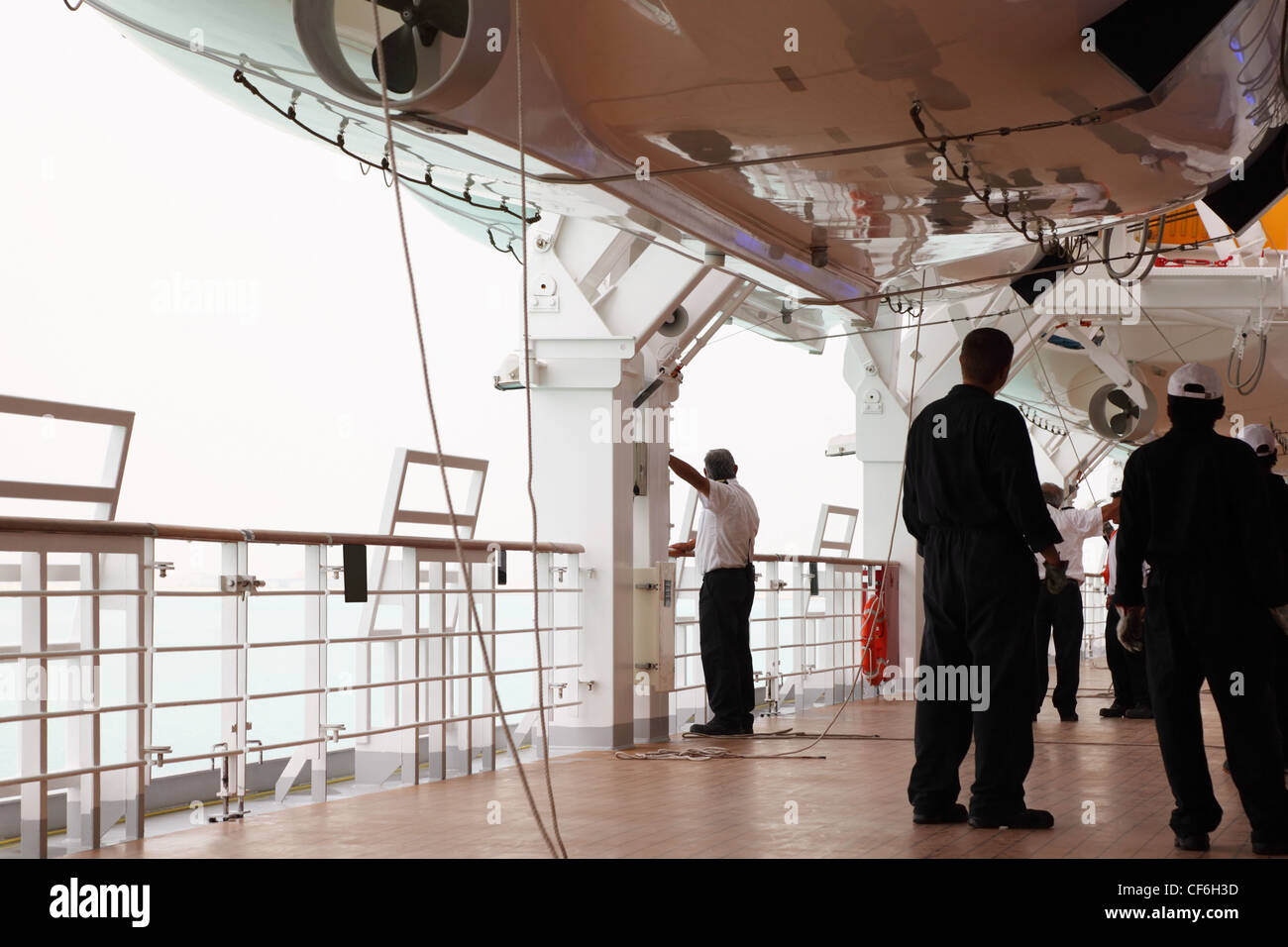 service staff in black uniform standing on cruise liner deck, view from back Stock Photo