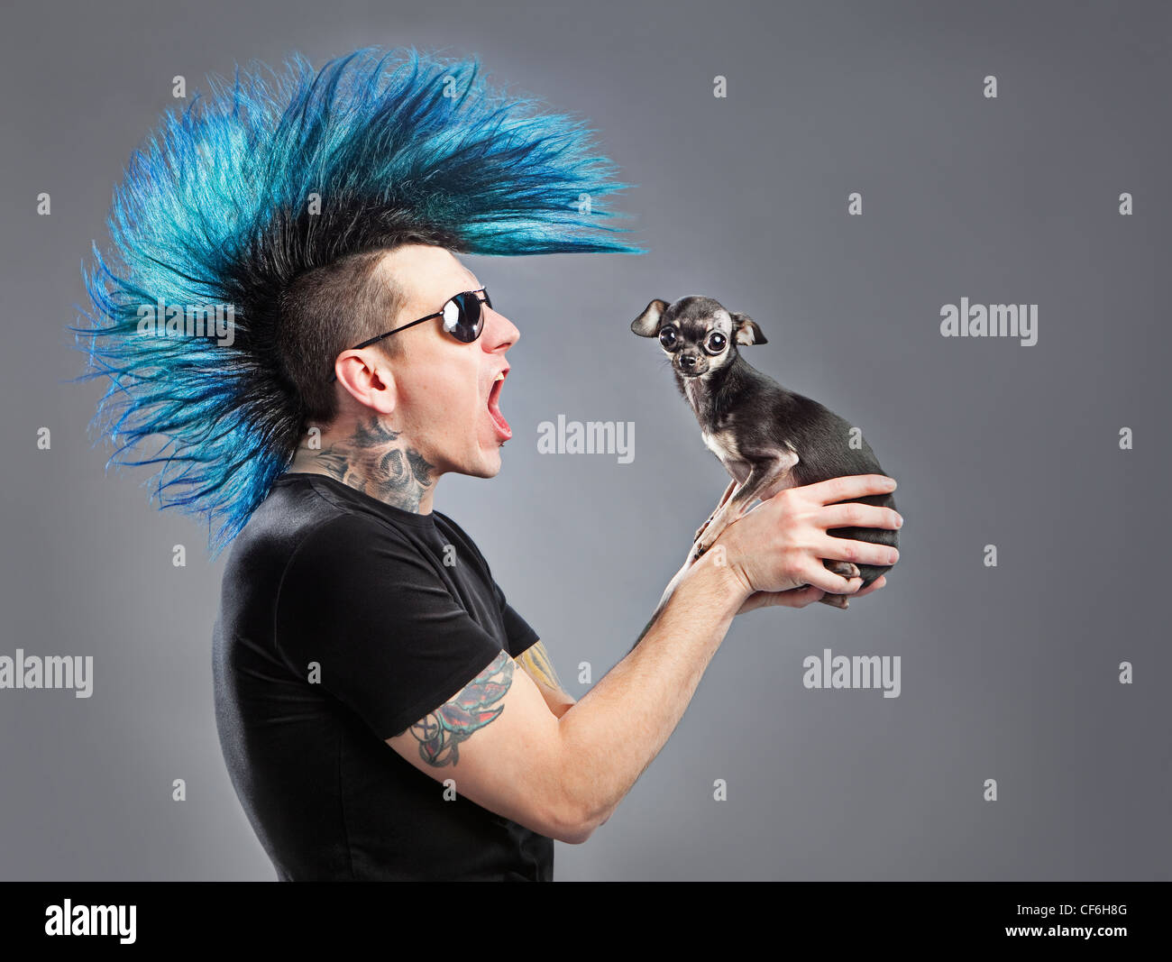 A Man With A Blue Mohawk Yells At His Dog Stock Photo