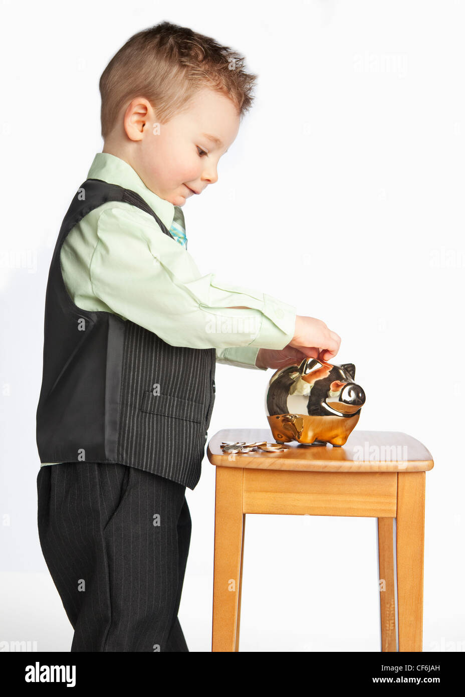 A Young Boy Wearing A Suit Putting Money In His Piggy Bank; Edmonton