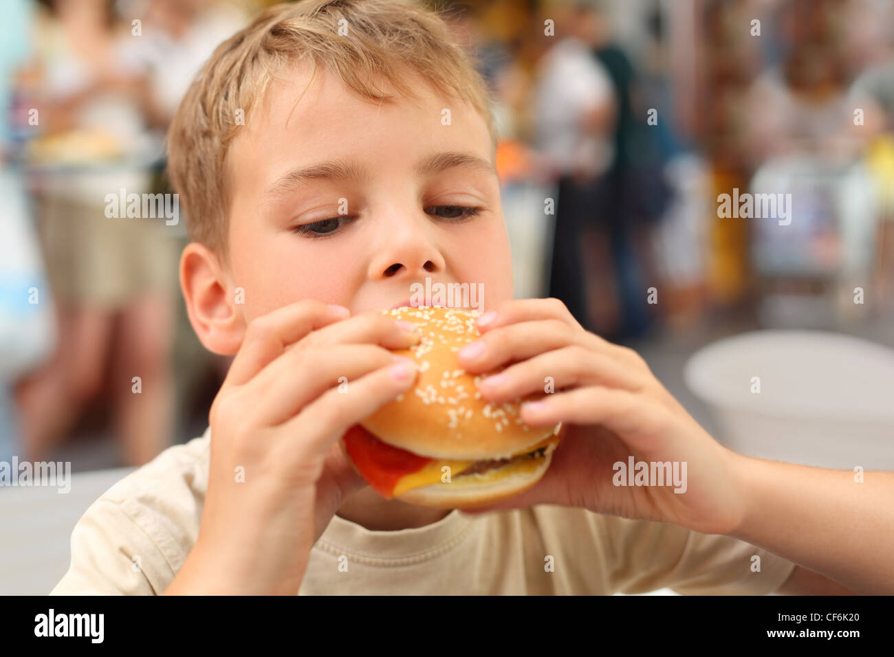 little caucasian boy eating burger, looking down Stock Photo Alamy