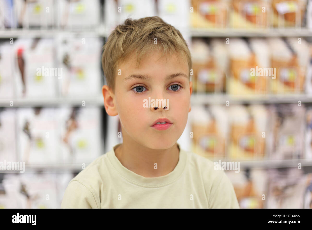 portrait of little caucasian boy looking at side, counter in store with commodity Stock Photo