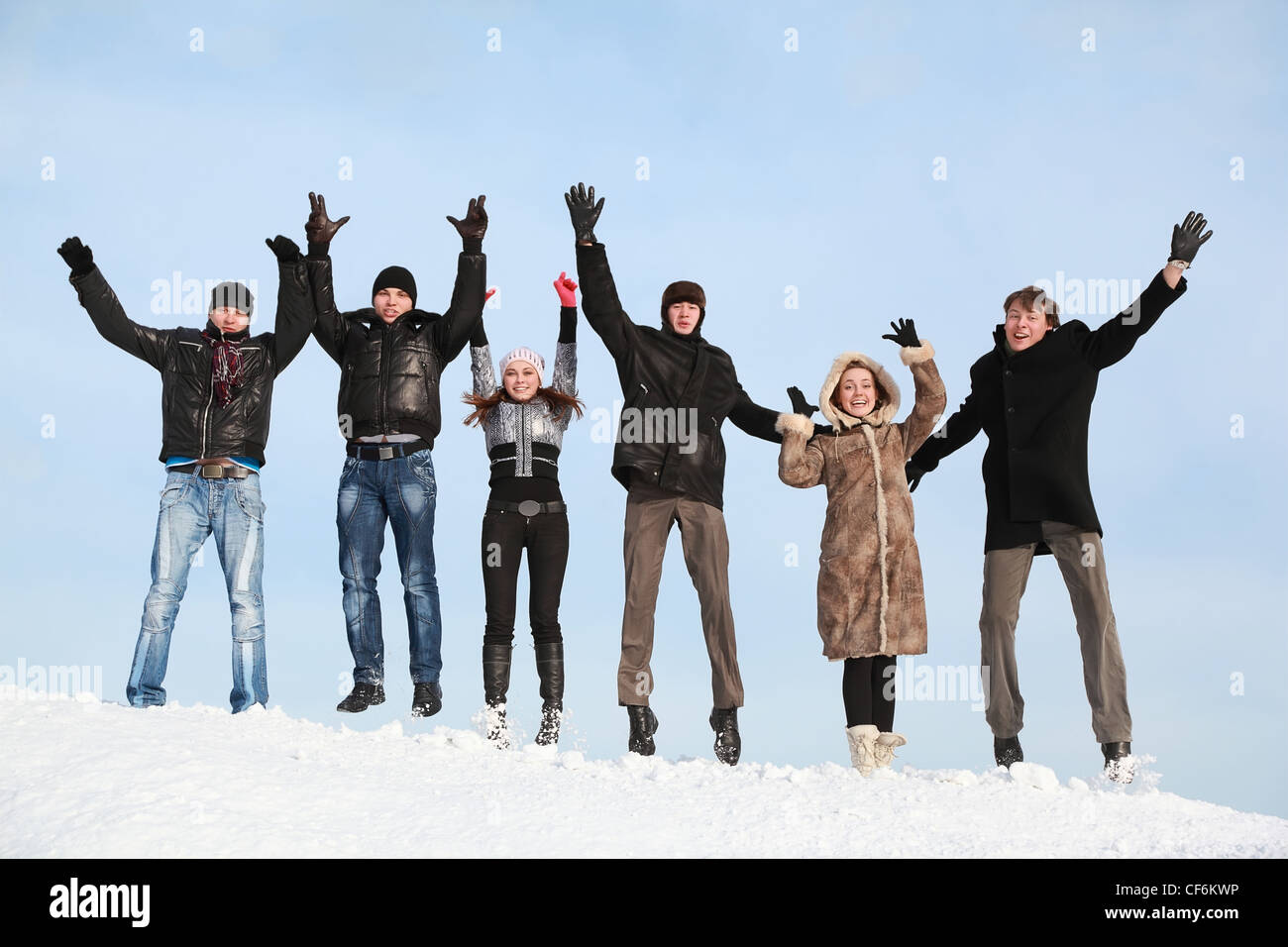 Young people jump in winter on snow and lift hands upwards Stock Photo