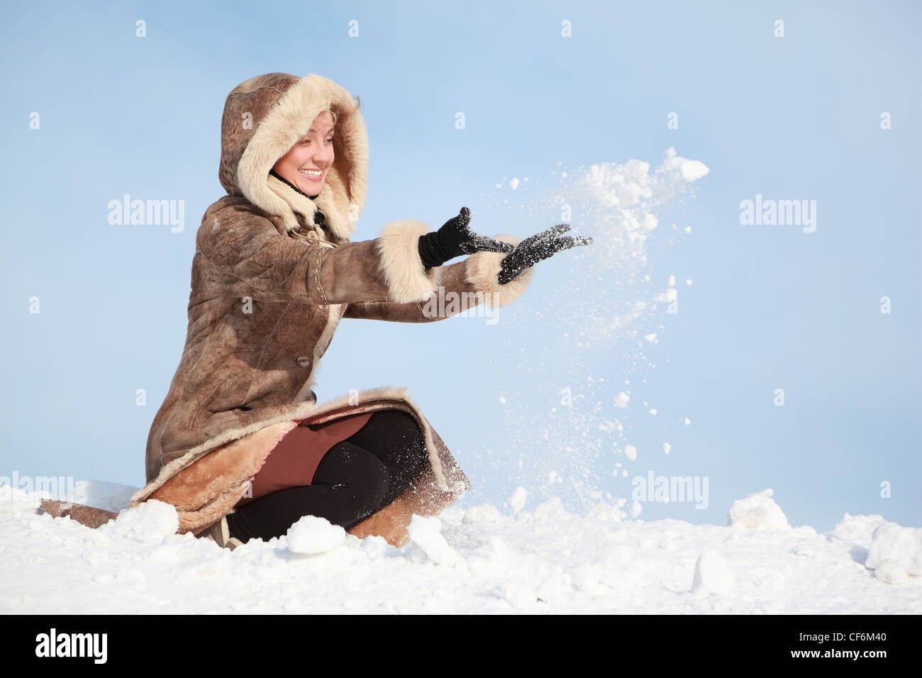 Young woman squatting and  hands throw snow Stock Photo