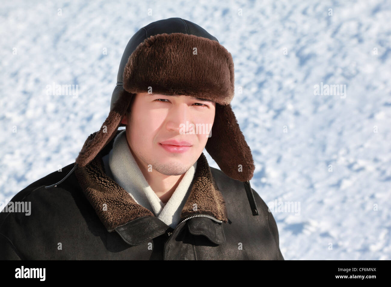 Young man stands in ear-flaps hat in winter and concentrated looks ahead Stock Photo