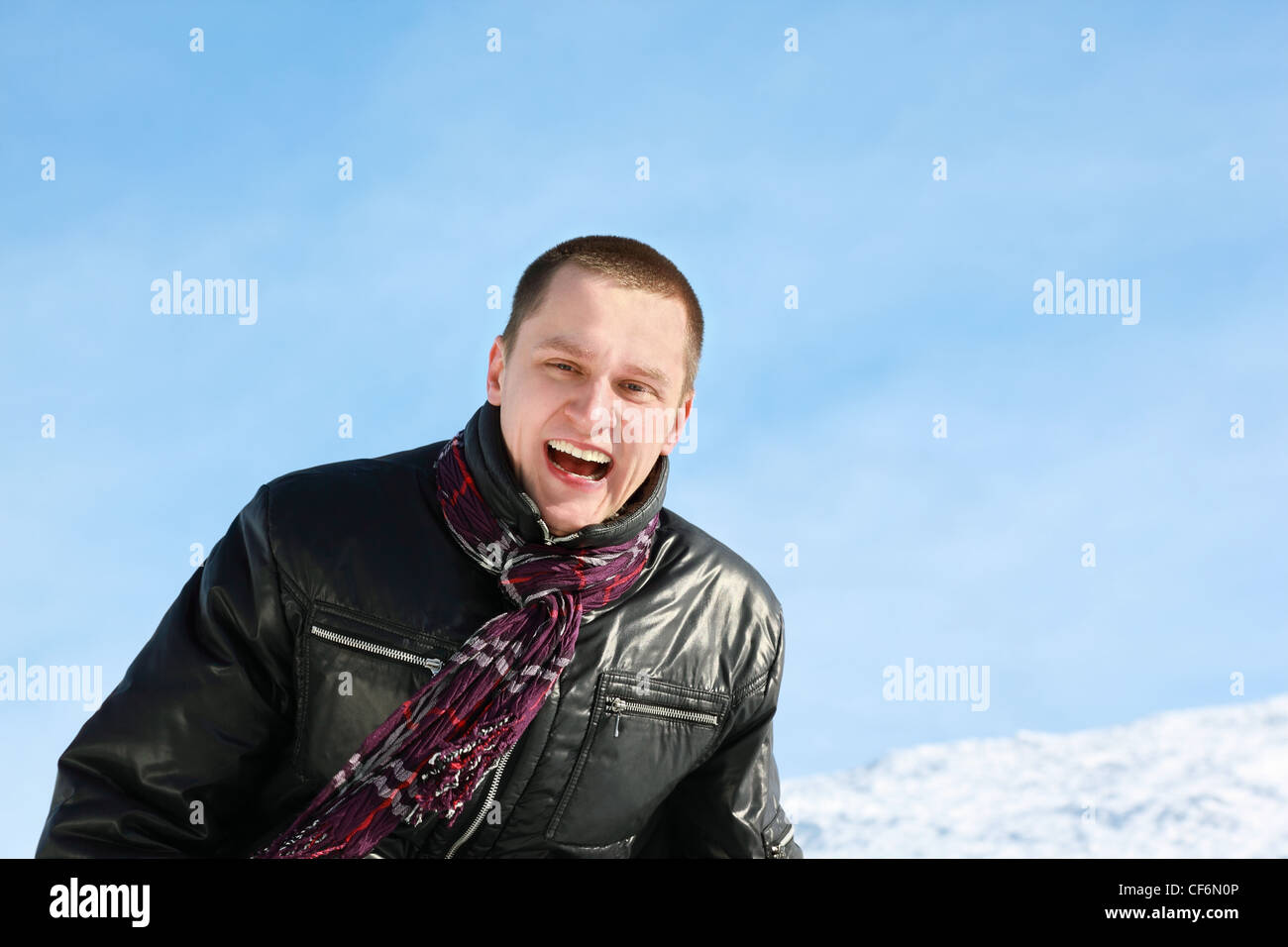Young man laughs merrily in day-time in street in winter Stock Photo