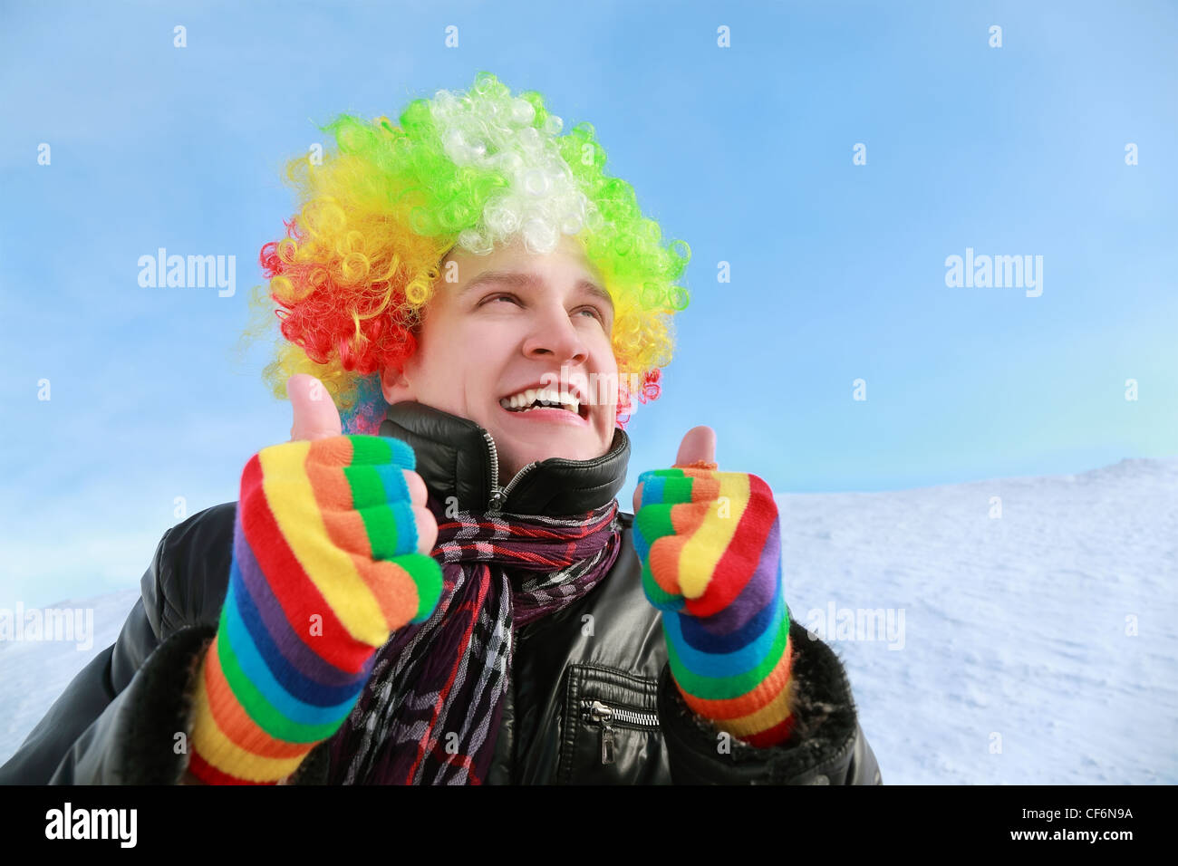 Man in wig and gloves of clown looks in sky and shows gestures hands Stock Photo
