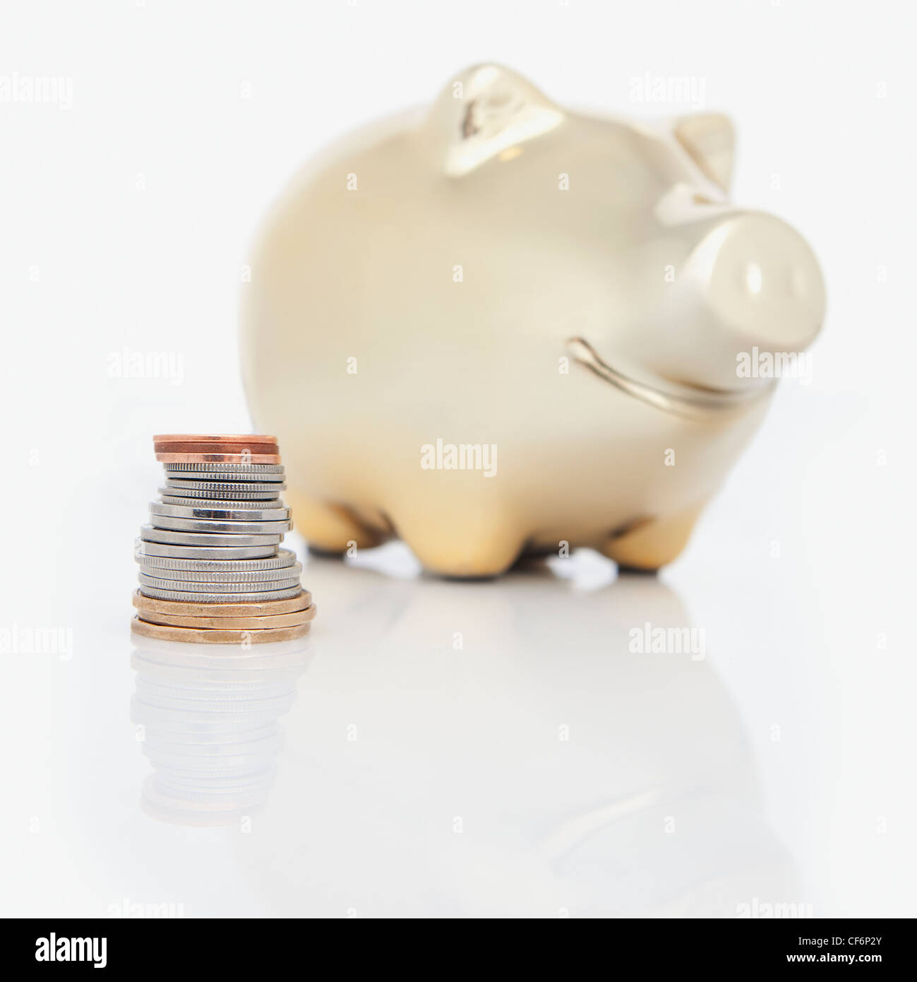 A Stack Of Coins Beside A Piggy Bank Stock Photo - Alamy