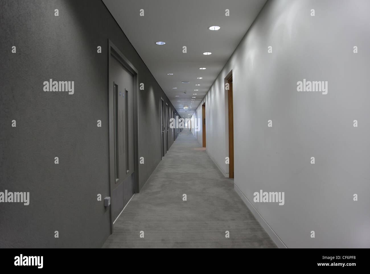 a long gray hallway with doors. light at the end of the corridor Stock Photo