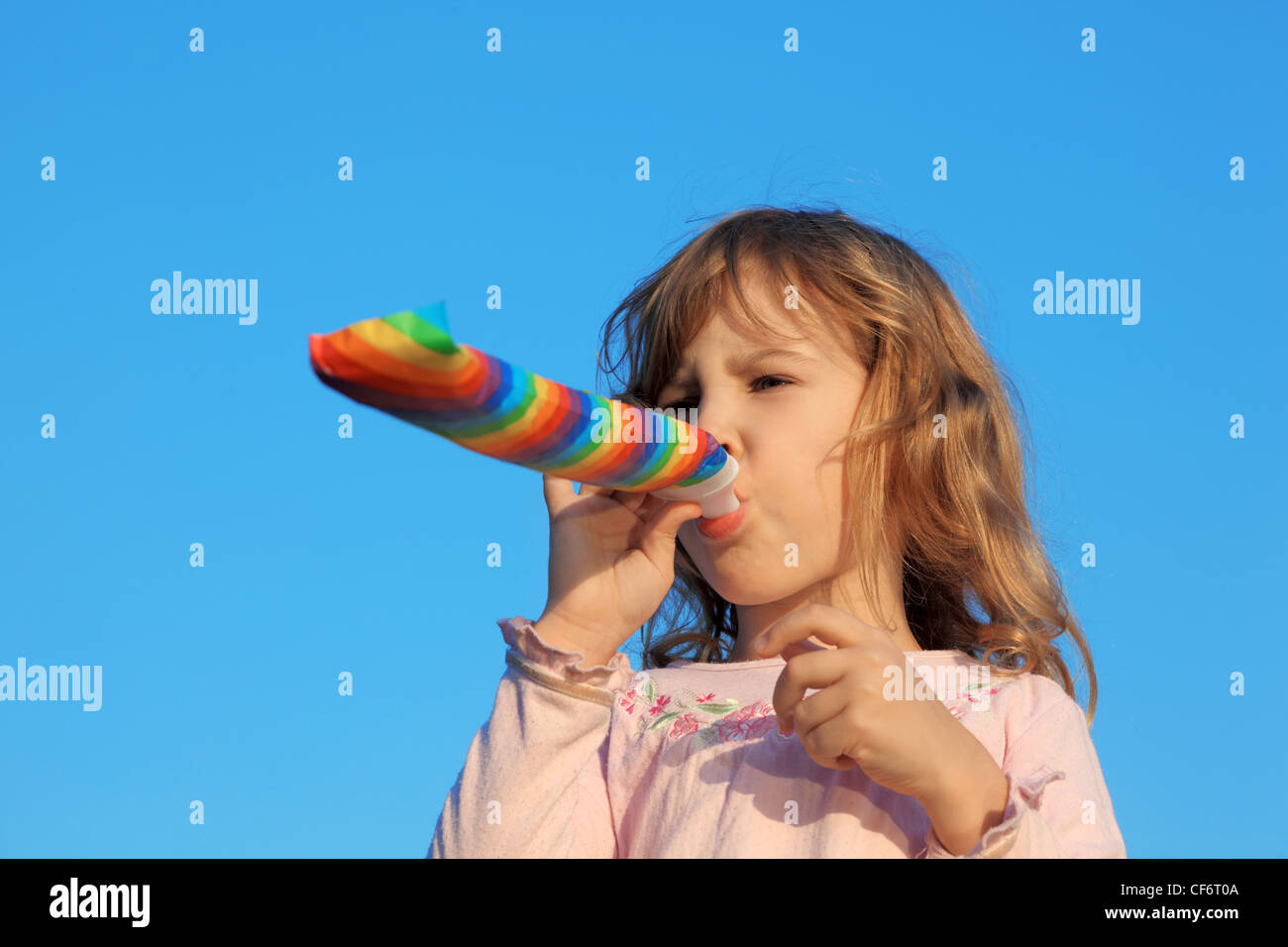 little girl with party blower on blue sky Stock Photo - Alamy