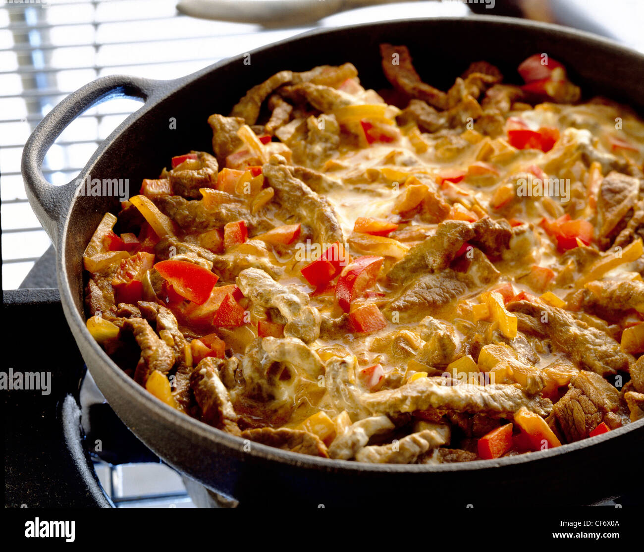 Tasty Autumn Casseroles Quick goulash, stewing steak, red peppers, onions and creamy sauce, in large black casserole dish Mat Stock Photo