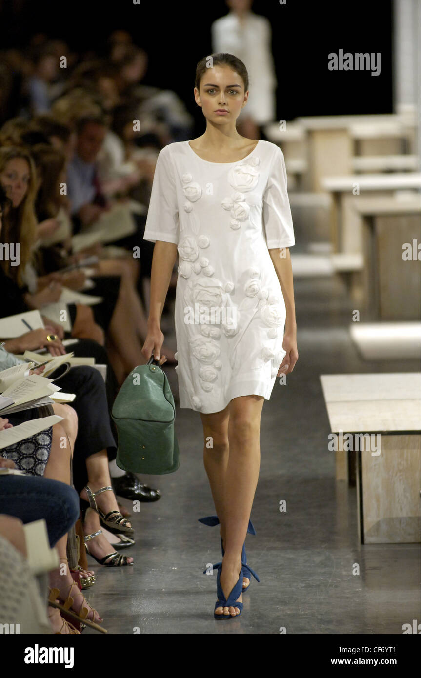 Philip Lim New York Ready to Wear Spring Summer Round neck white shift dress  floral corsages, worn blue sandals and big green Stock Photo - Alamy