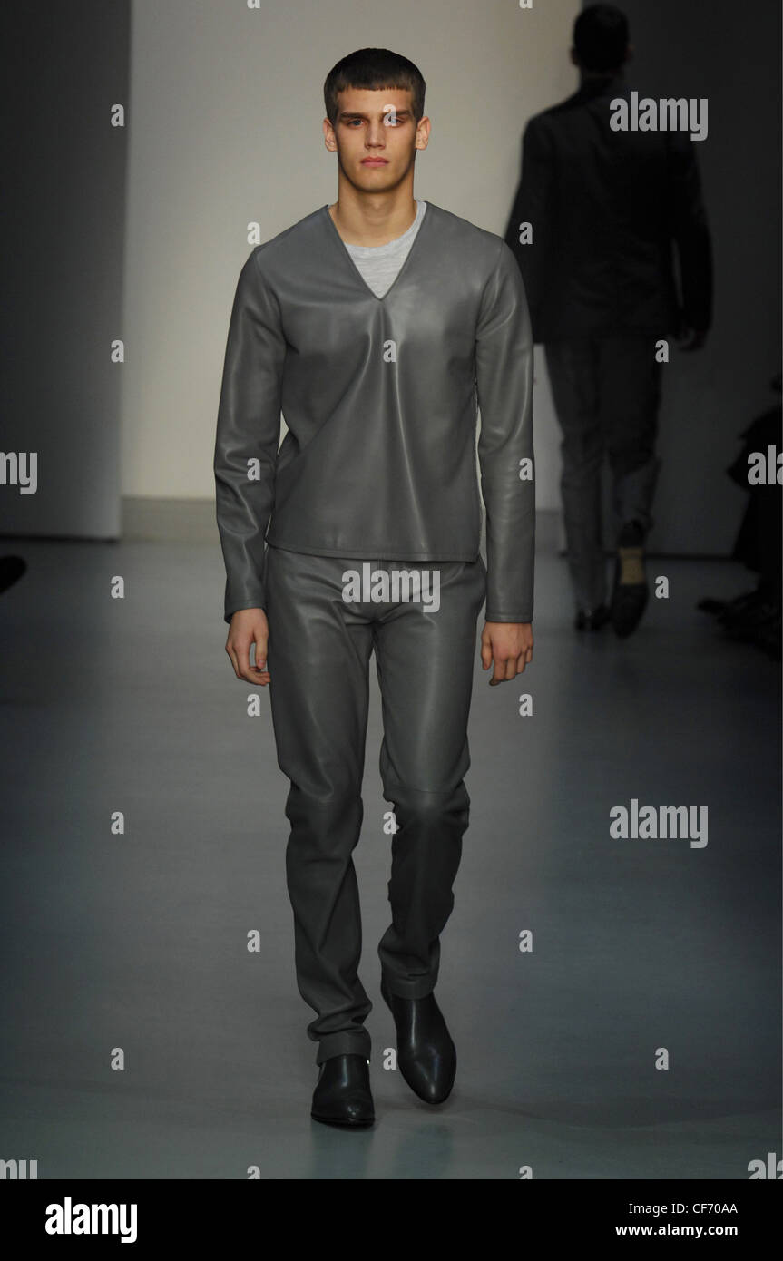 Calvin Klein Milan Menswear Ready to Wear Autumn Winter Male model wearing two piece grey V neck leather shirt and matching Stock Photo