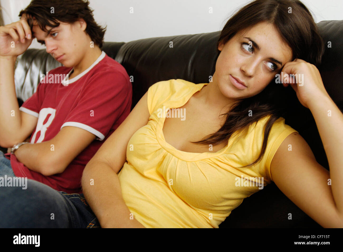 Couple sitting on sofa turned away from each other unsmiling Stock Photo
