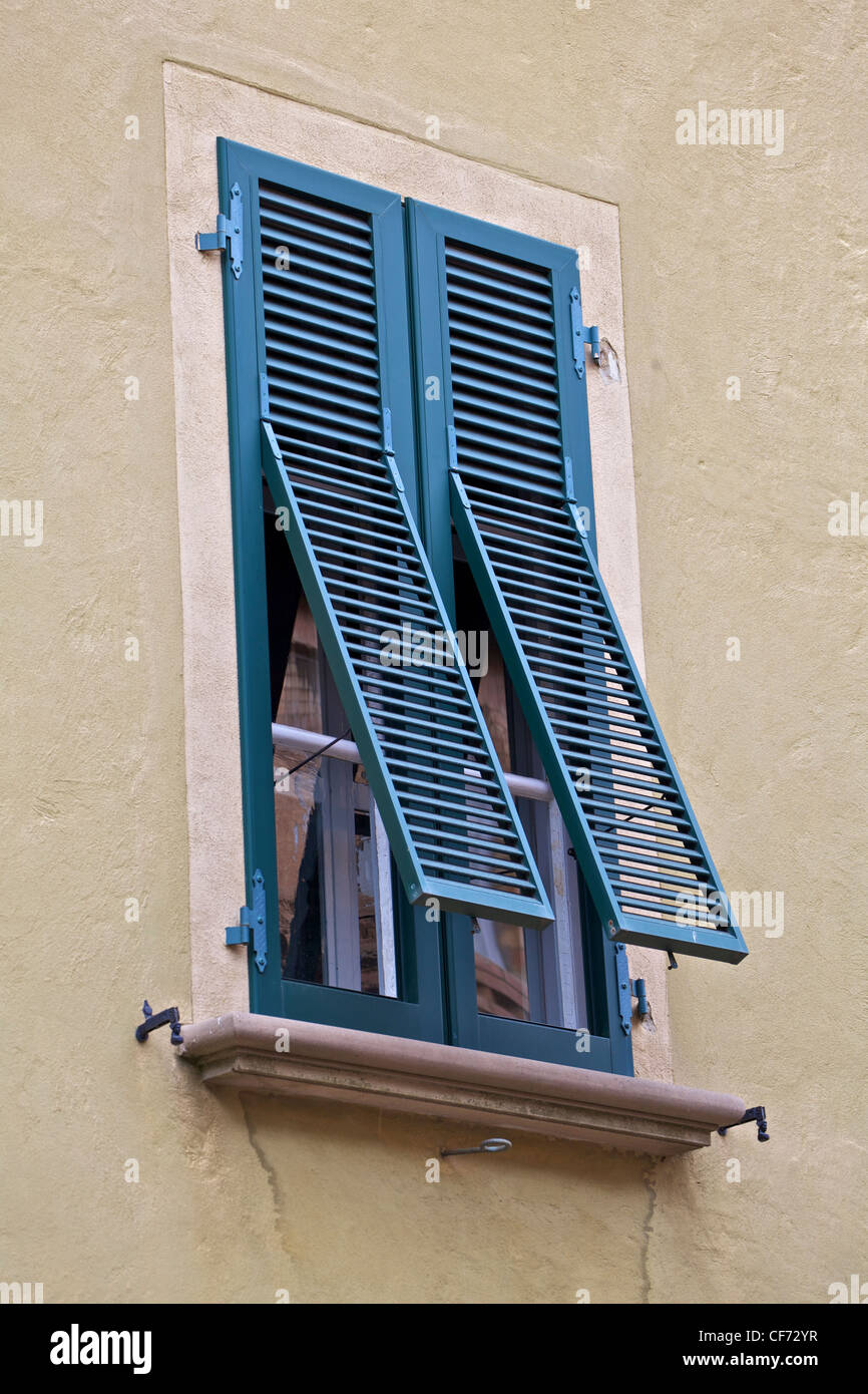 Green Wood Open Shutters on a Weathered Plaster Wall in Tuscany Stock Photo