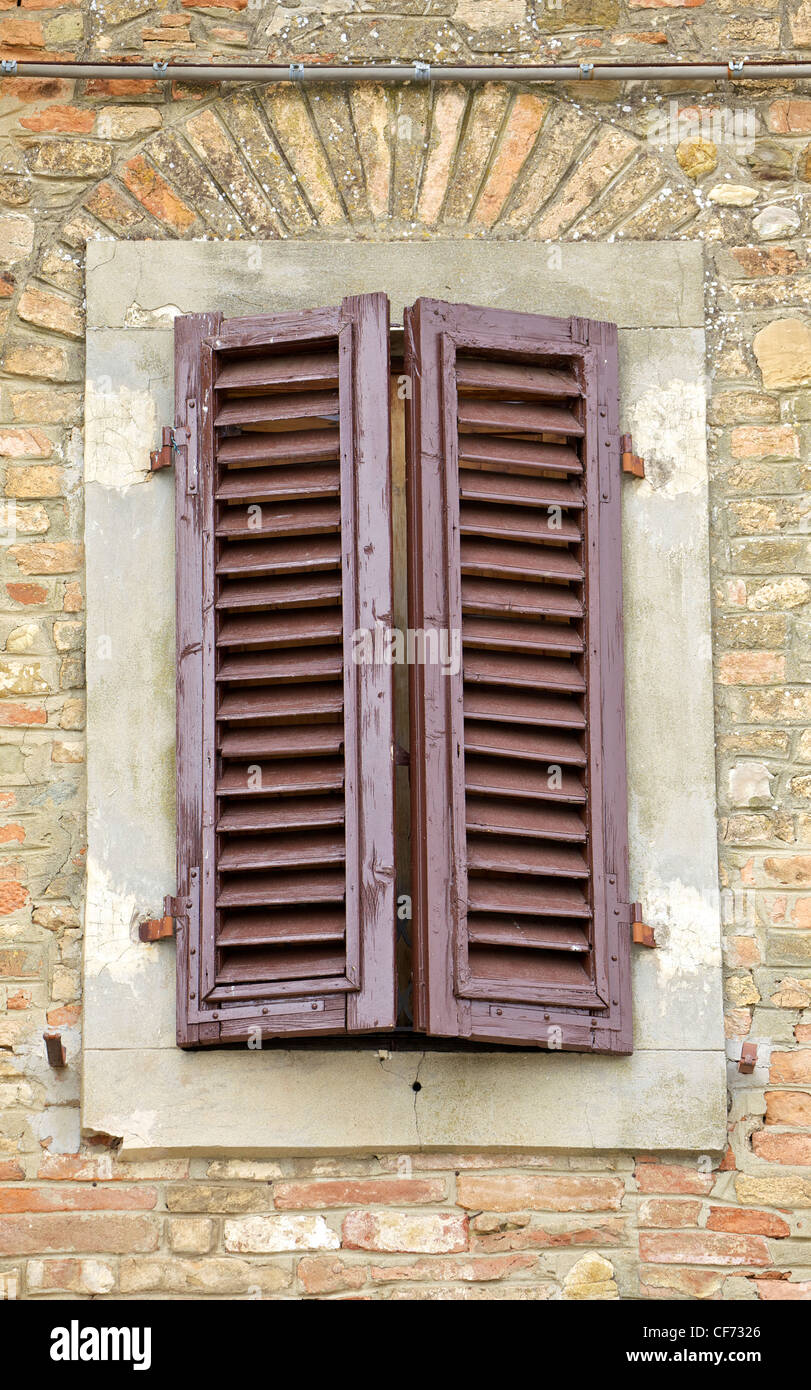 Brown Wood Shutters on an Exposed Brick Wall in Tuscany Stock Photo