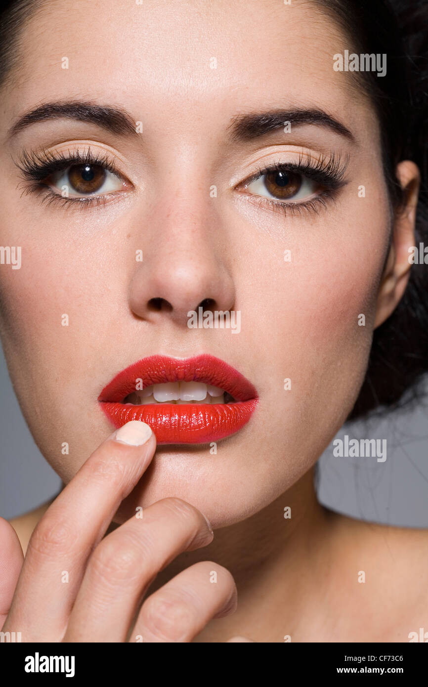 Female wearing glamorous make up long false eyelashes, black eyeliner in a  flick and bright red lipstick, touching her lip a Stock Photo - Alamy