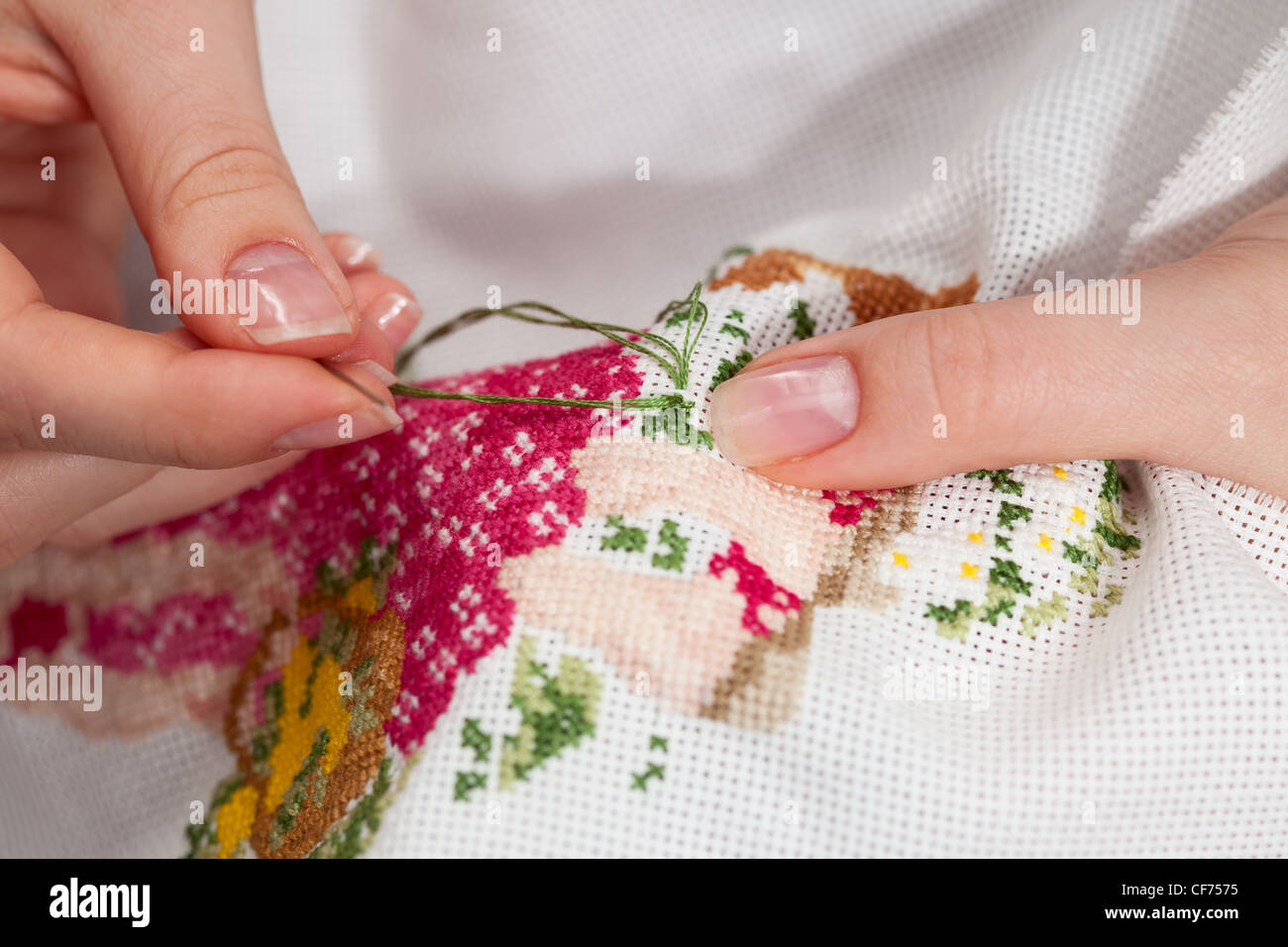 Woman hands doing cross-stitch. A close up of embroidery. Stock Photo