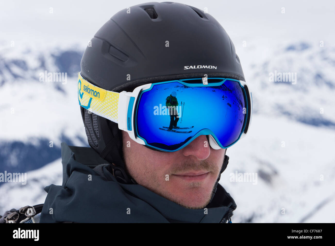 Man wearing a Salomon skiing helmet with a skier on snow reflected in a  pair of blue ski goggles Stock Photo - Alamy