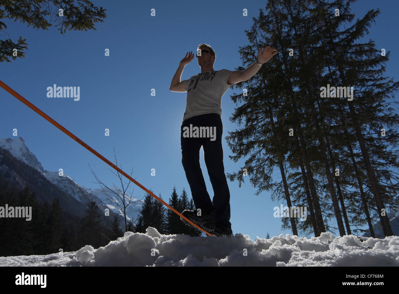 Man walking on a slackline in Chamonix valley with alpine mountains in