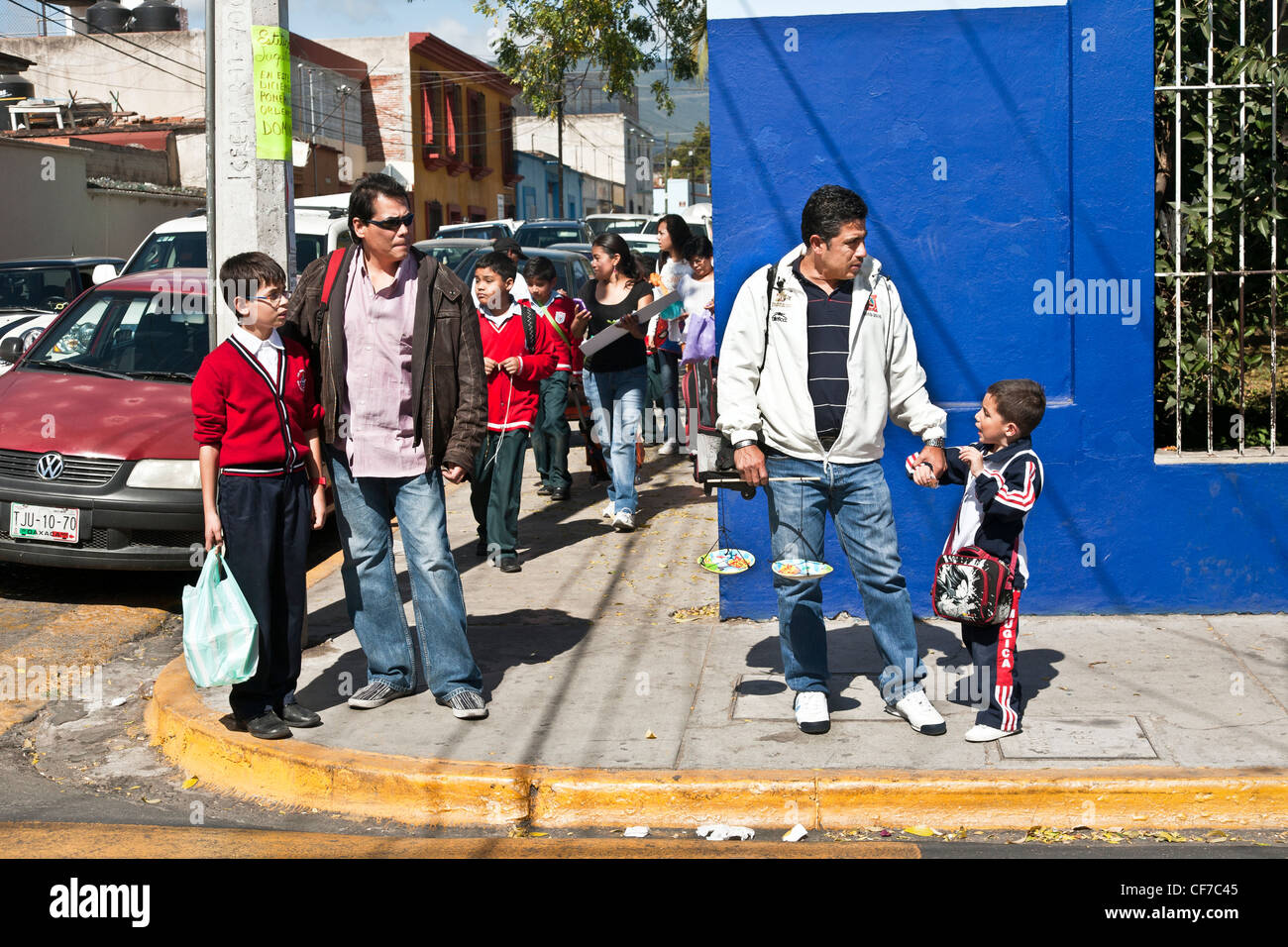 two macho Mexican fathers on street corner walking young schoolboy sons home after picking them up from classes Oaxaca Mexico Stock Photo