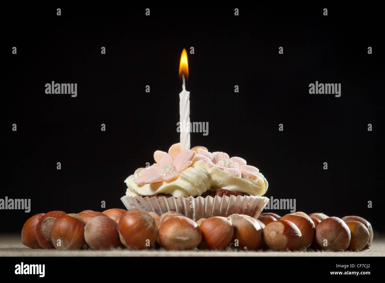 Muffin with small burning candle and hazelnuts Stock Photo