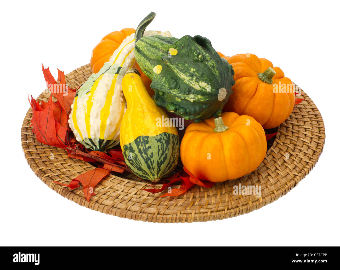 Colorful arrangement of fall leaves and decorative gourds on a wicker tray isolated on white Stock Photo