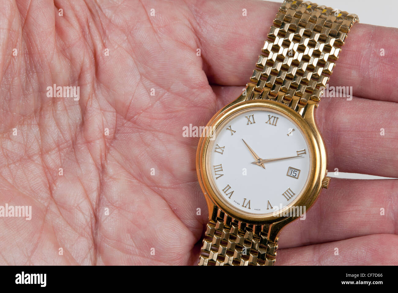 Gold watch and band in close up in palm of hand across fingers Stock Photo