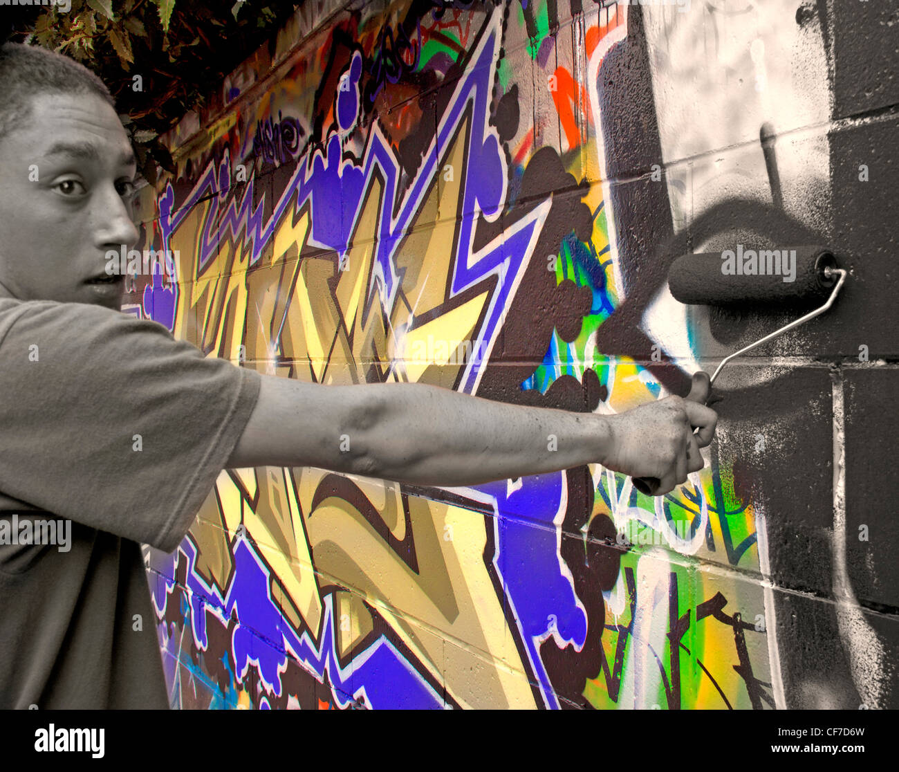 Removing colourful graffiti with a paint roller covered in black paint, Potterrow, Edinburgh, Lothian, Scotland, UK Stock Photo