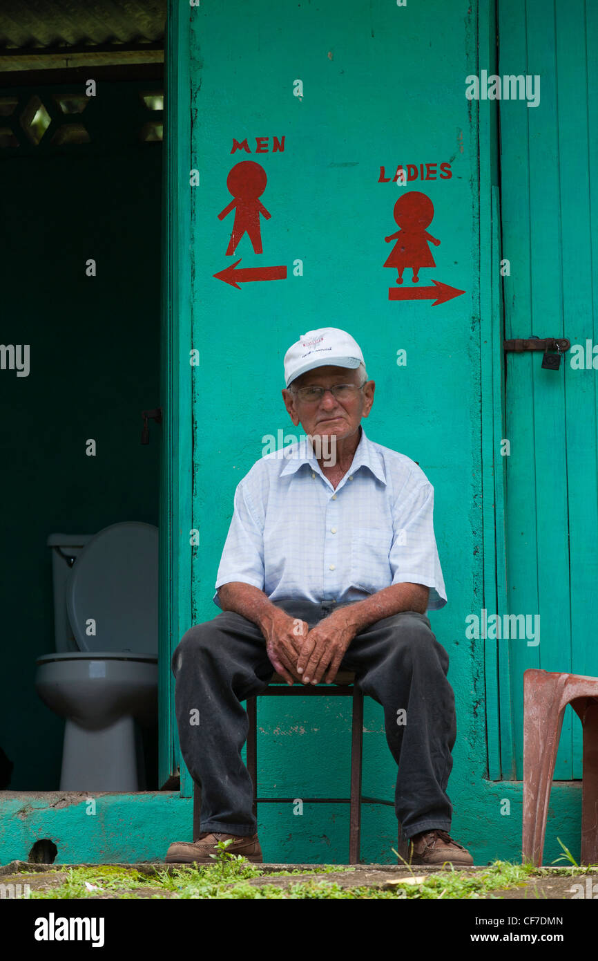 A Costa Rican attendent sits by the doors of the mens and woman's