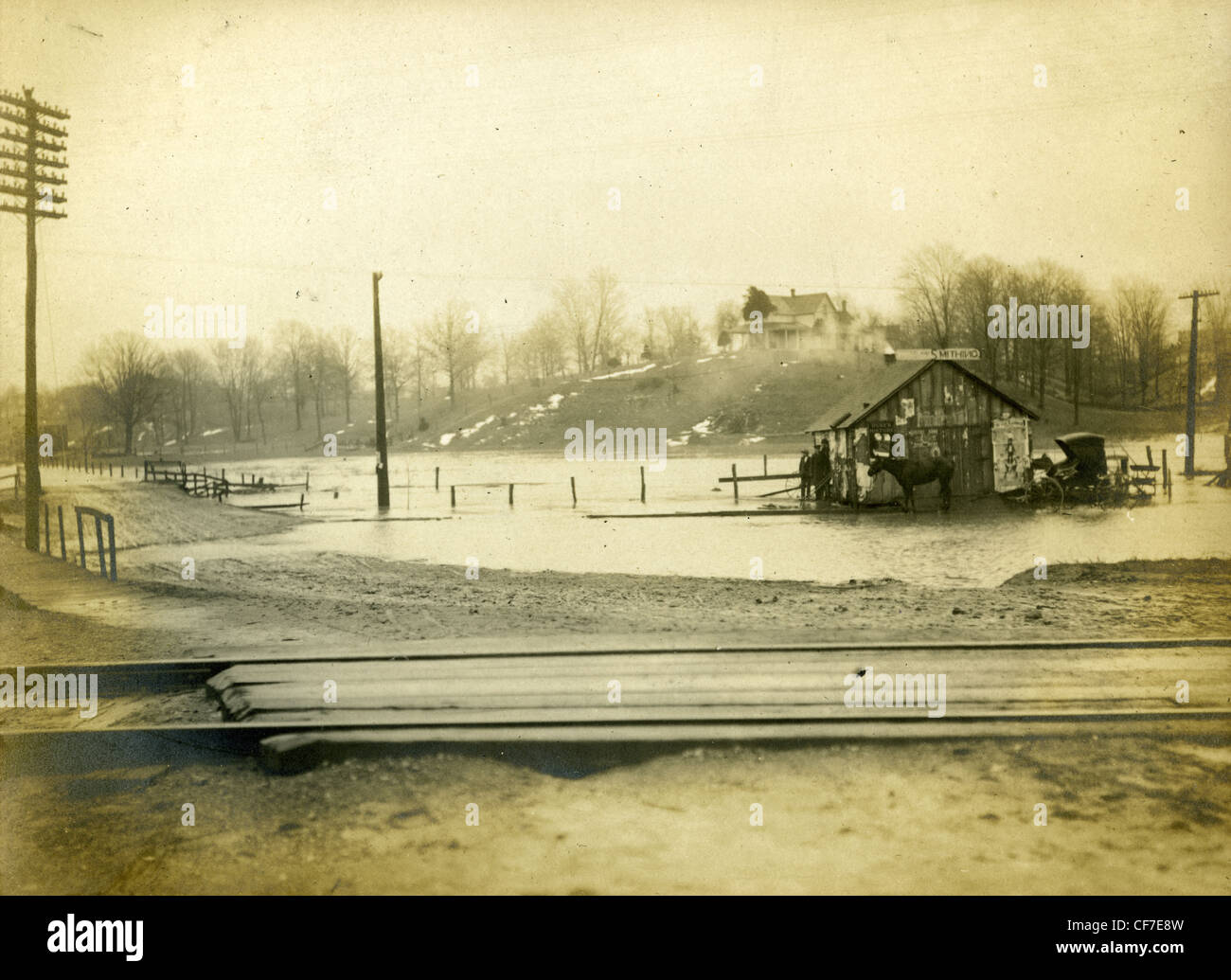 A blacksmith's stable is surrounded by water near railroad tracks in Indiana during the early 1900s. flooding black smith horses Stock Photo