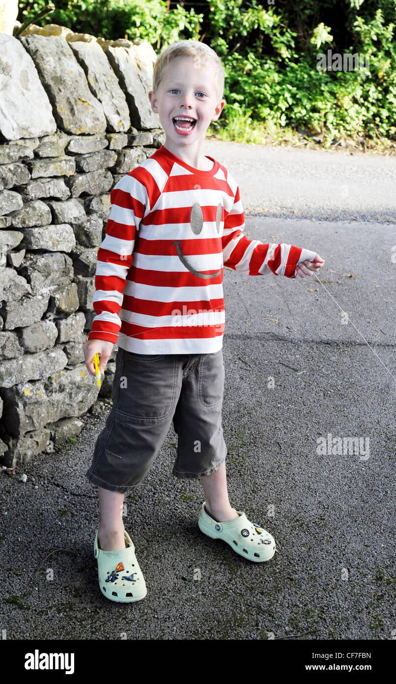 A young male wearing a white and red striped long sleeve jumper grey long shorts and pale green croc clogs holding the Stock Photo Alamy